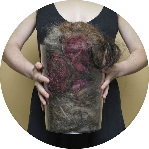 A woman holding a bucket full of hair ready to be composted.