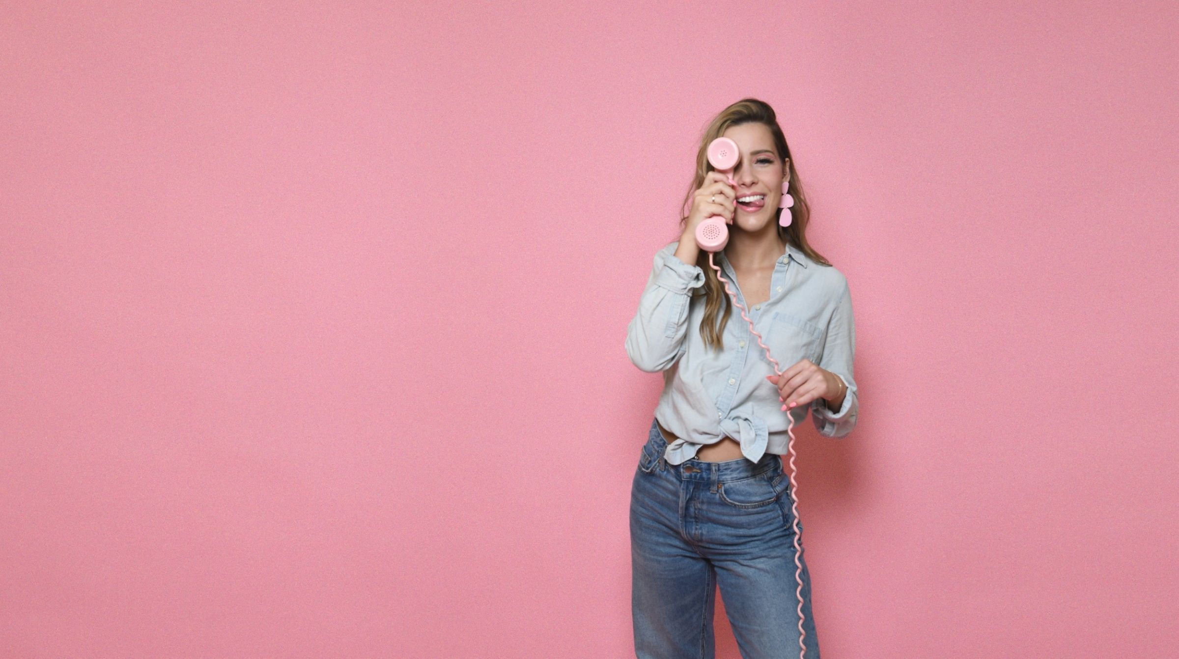 A young woman is holding a phone against a pink background on the salon FAQ page