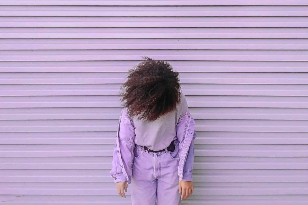 A woman posing in front of a purple wall in a hair salon.